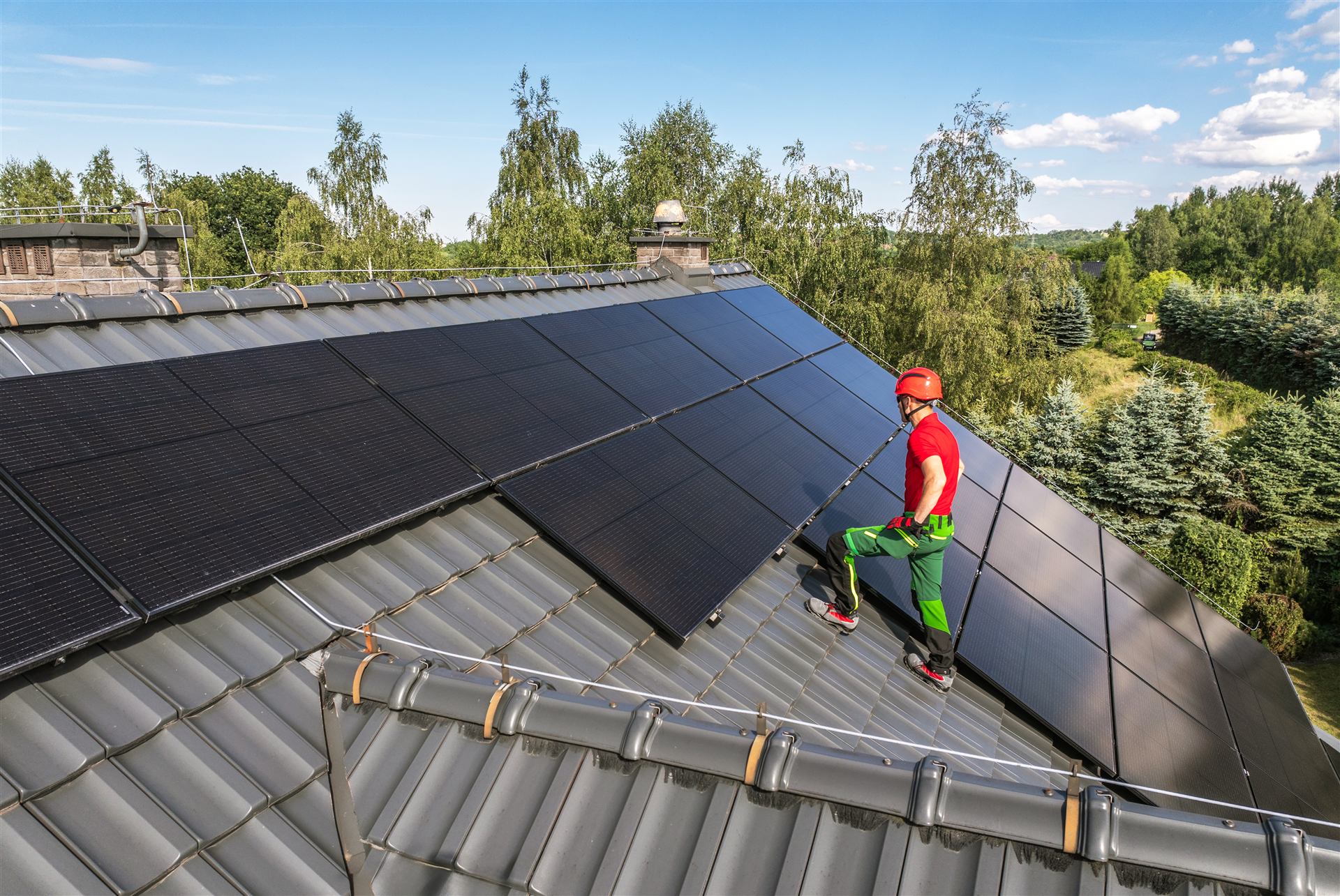 Techniker montiert Solarmodule auf einem Ziegeldach